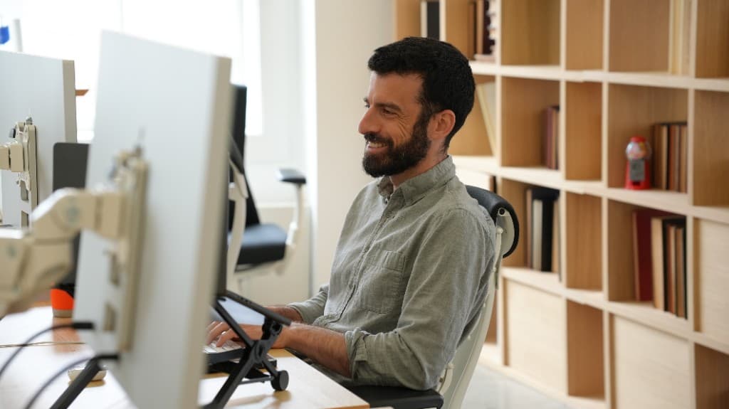 A Cohorvaer smiling at his desk by the office bookshelves