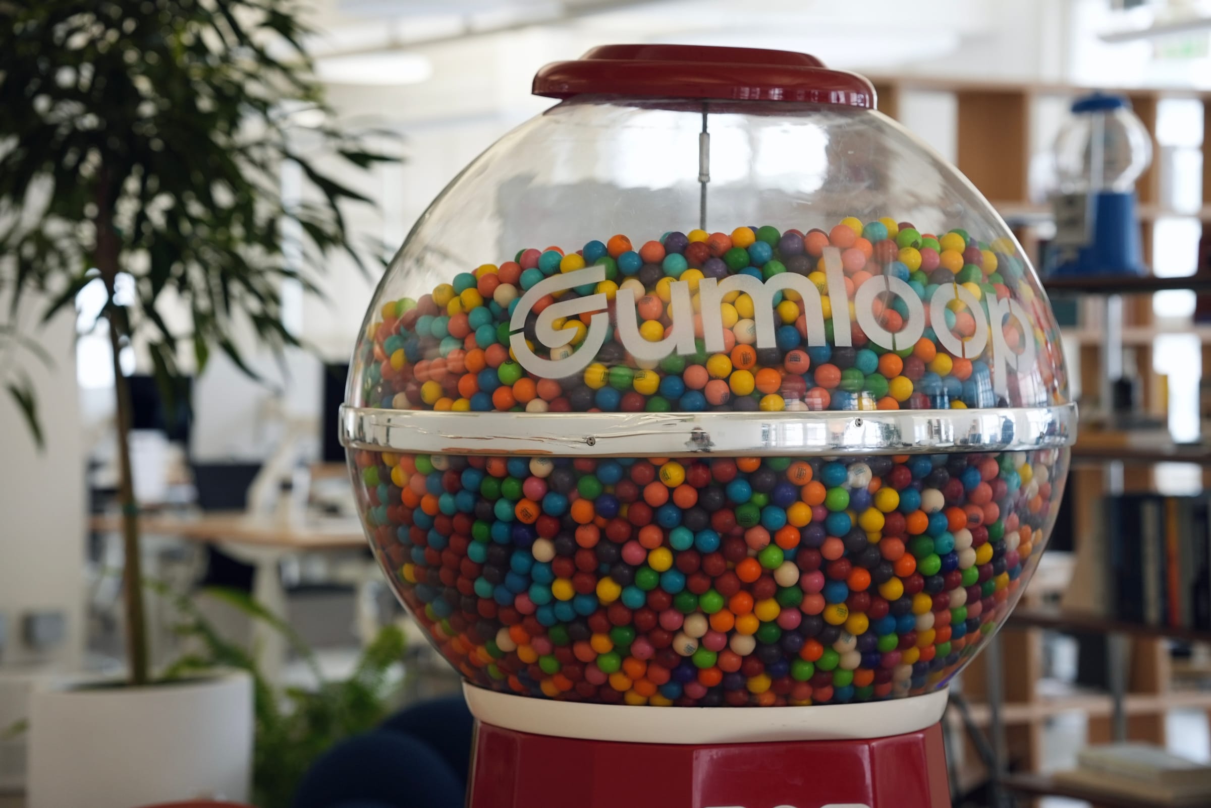 The Cohorva-branded gumball machine standing on the office floor, packed with coloured gumballs