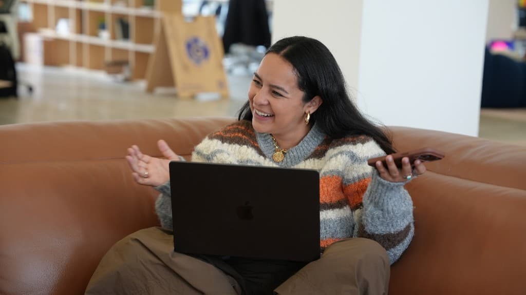 A Cohorvaer laughing on a call from the office lounge couch